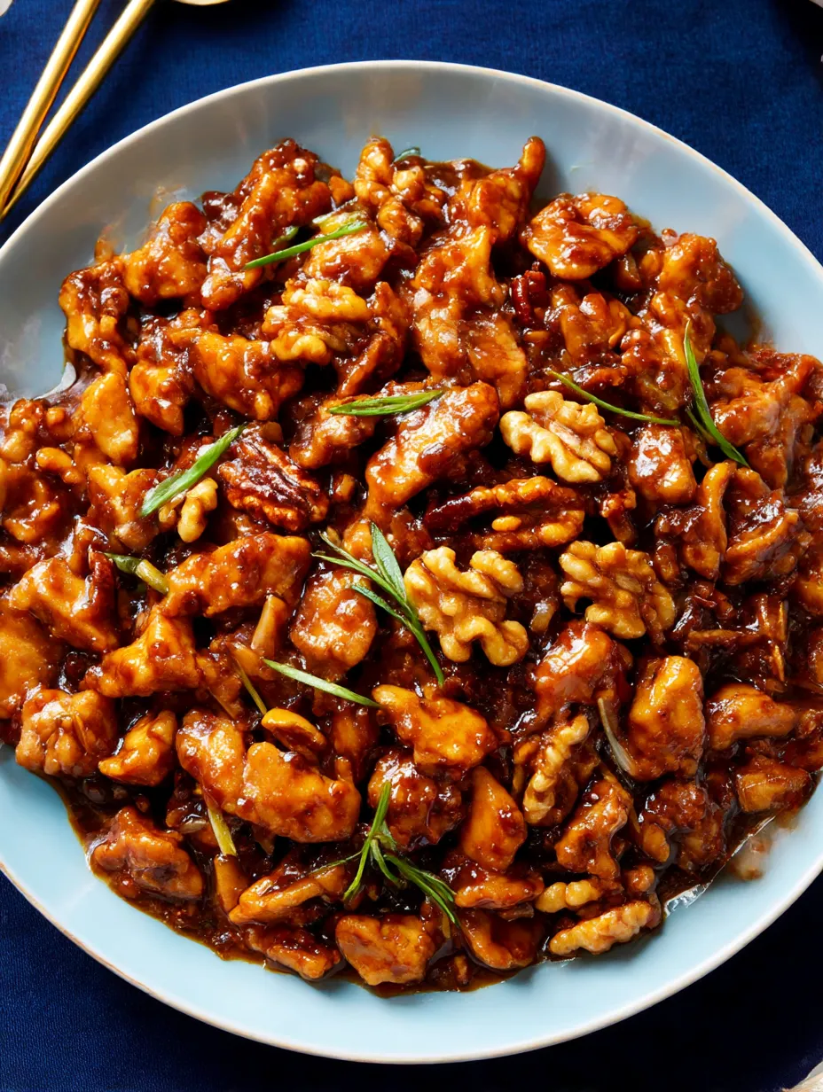 A plate of chicken with nuts and sauce.