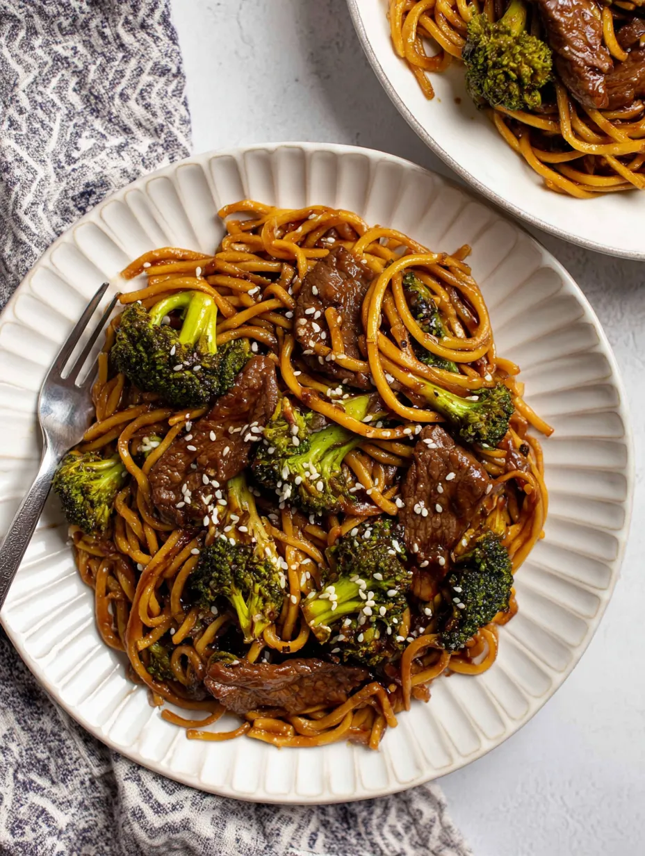 A plate of noodles with meat and broccoli.