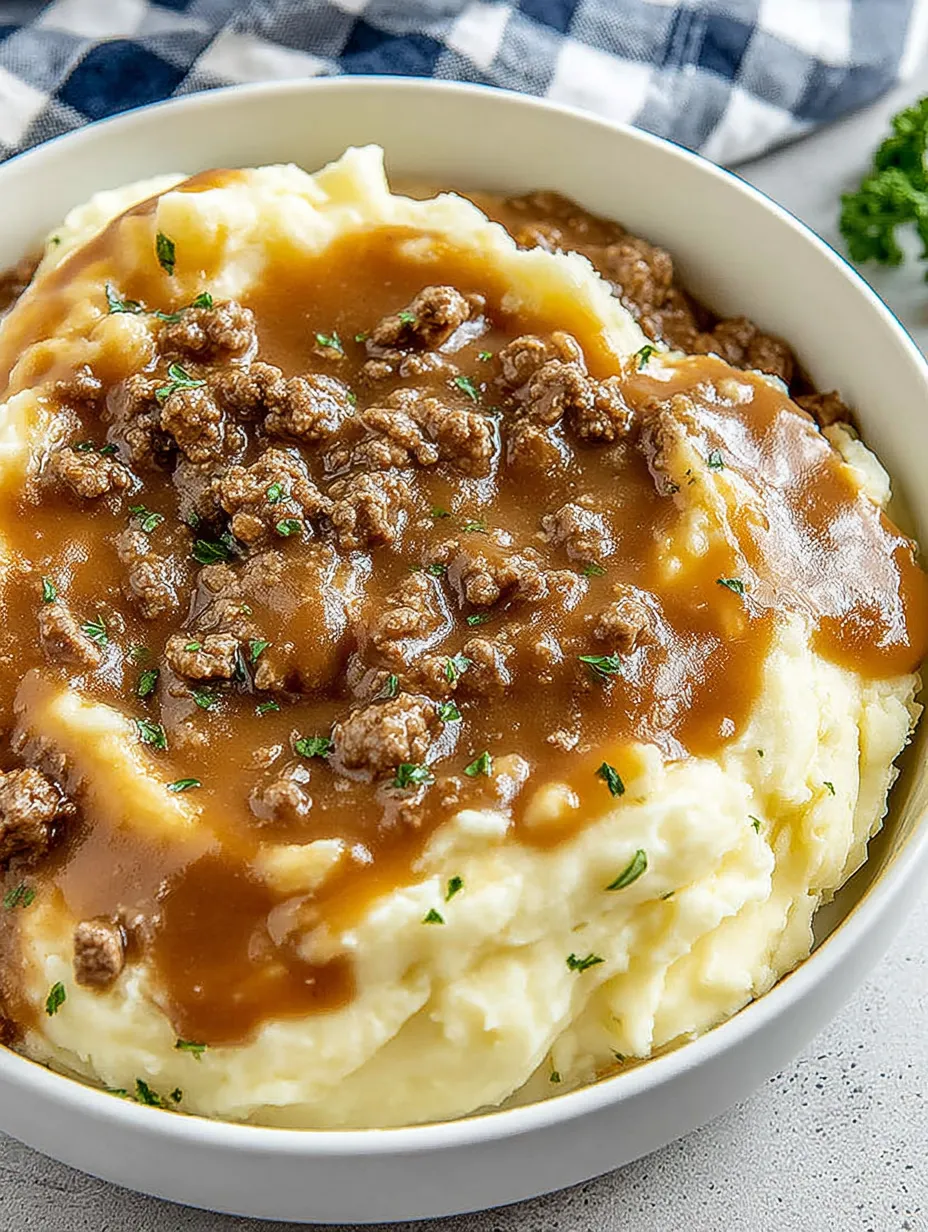 A bowl of mashed potatoes with meat and gravy.