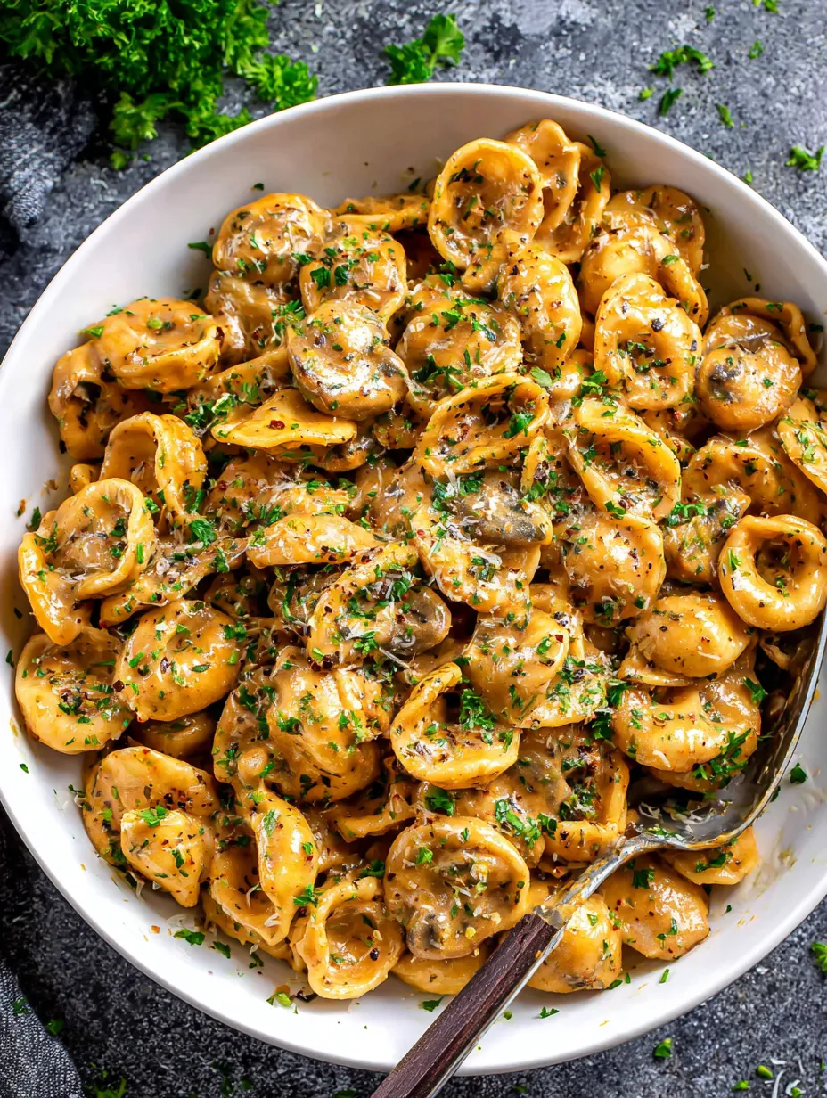 A bowl of pasta with mushrooms and herbs.