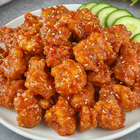A plate of Chinese Honey Chicken with cucumbers on the side.