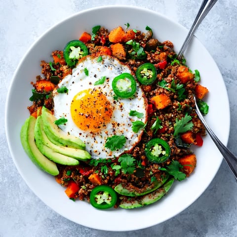 A bowl of Tex-Mex Sweet Potato Hash (Whole30) with a fried egg on top.