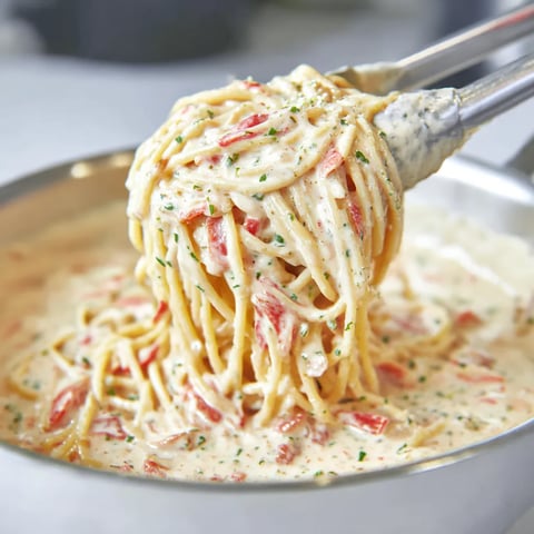 A spoon is scooping up a bowl of pasta.