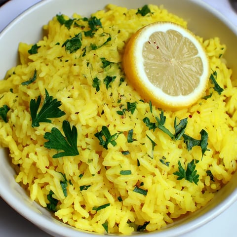 A bowl of yellow rice with a lemon wedge on top.