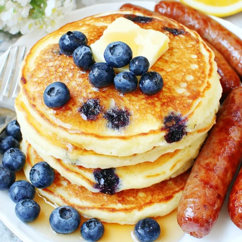 A stack of pancakes with blueberries and butter on top.