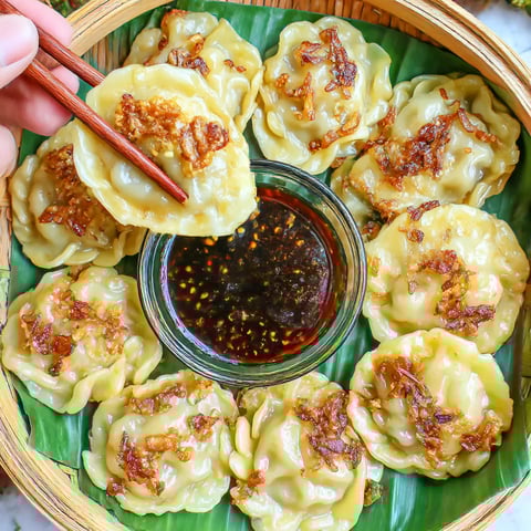 A person is holding a bowl of food with chopsticks.