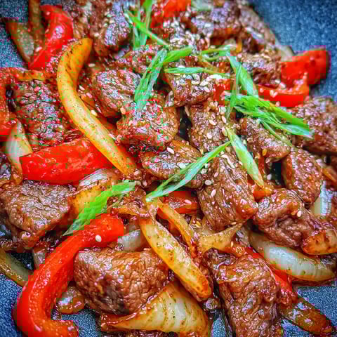 A plate of sizzling Chinese pepper steak with onions.