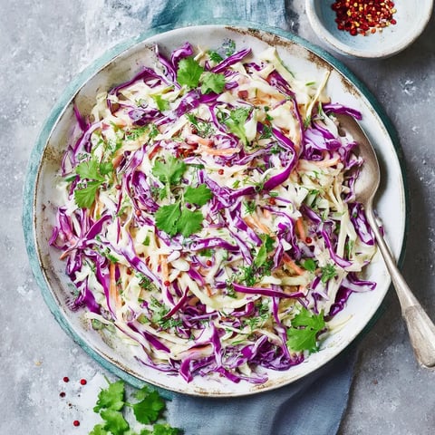 A bowl of coleslaw with a spoon in it.