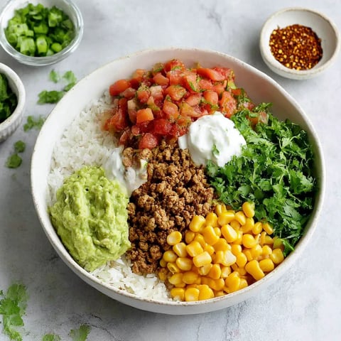 A bowl of food with rice, tomatoes, corn, and avocado.