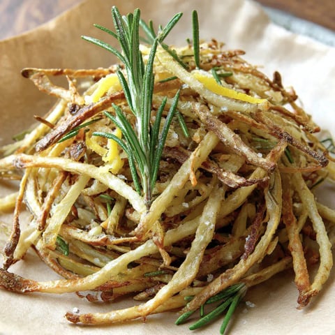 A plate of fries with lemon salt and rosemary.
