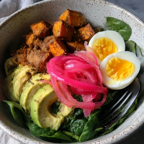 A bowl of food with eggs, sweet potatoes, and greens.