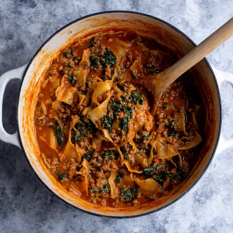 A bowl of lasagna soup with a spoon in it.