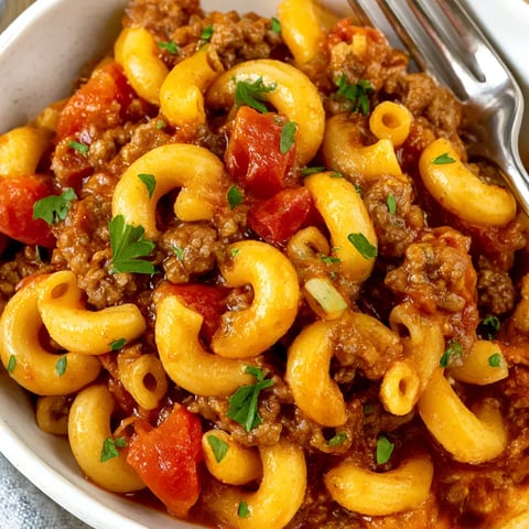 A bowl of slow cooker goulash with pasta and tomatoes.