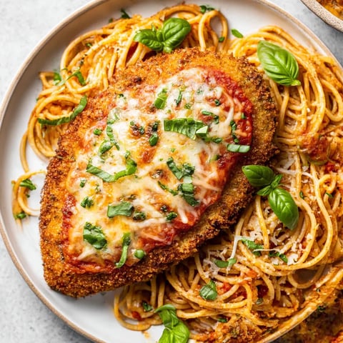 A plate of chicken with pasta and green herbs.