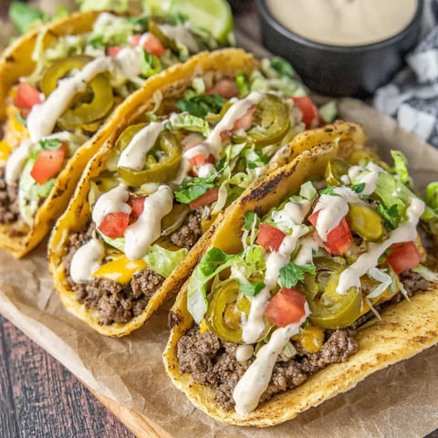 Two tacos with lettuce and tomatoes.