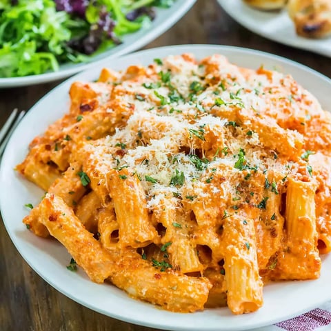 A plate of pasta with cheese and sauce.