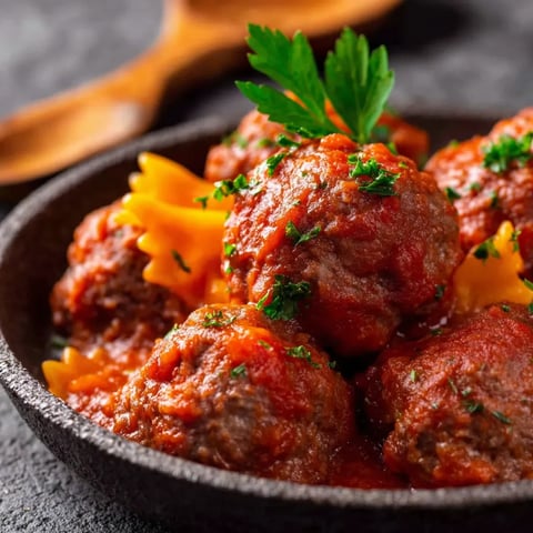 A bowl of meatballs with a spoon.