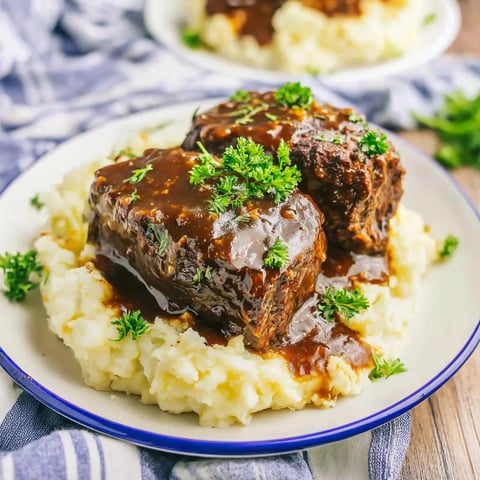 A plate of meat with gravy on it.