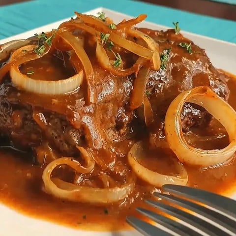 A plate of meat with onions on top.