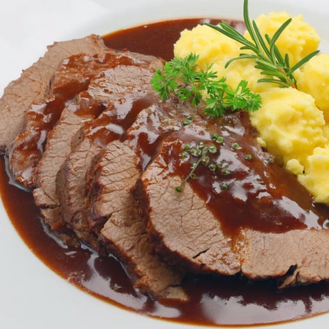 A plate of meat with gravy and mashed potatoes.