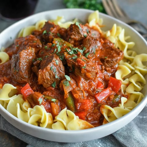 A bowl of pasta with meat and tomatoes.