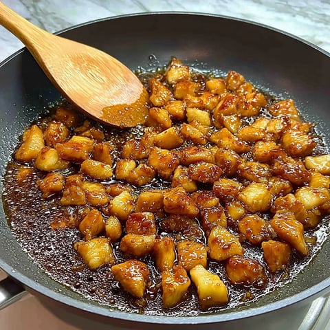 A wooden spoon in a pan with food.