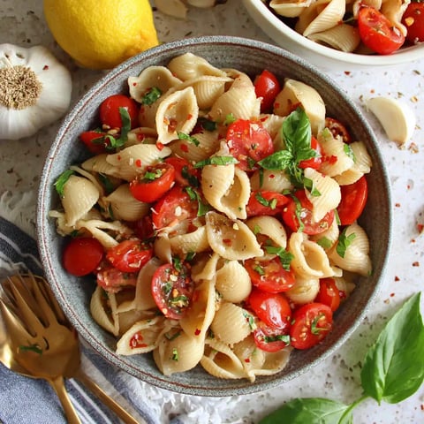 A bowl of pasta with tomatoes and basil.