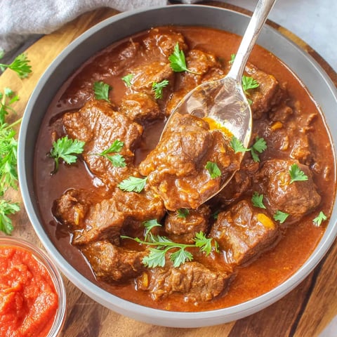 A bowl of meat with a spoon in it.